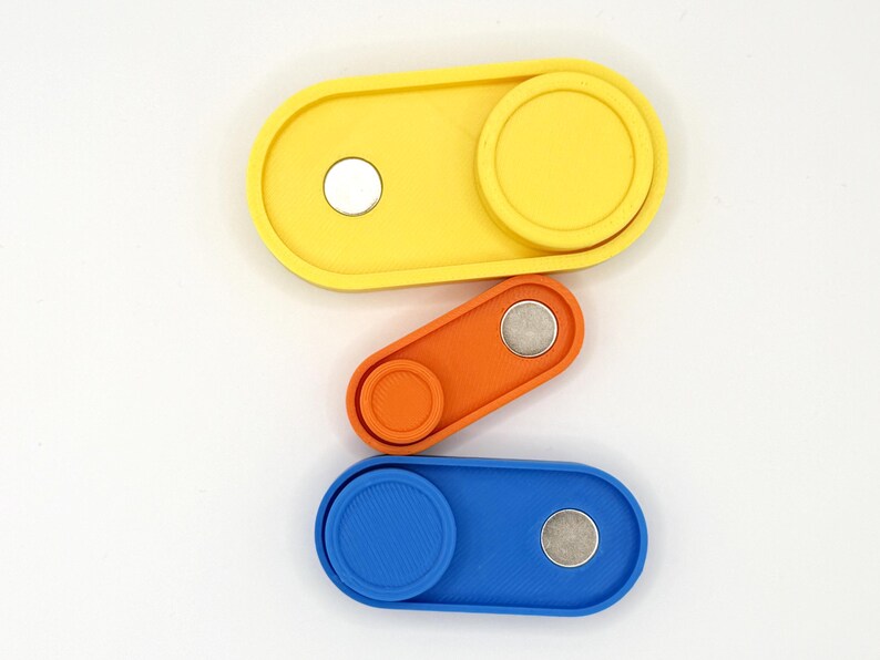 May include: Three colorful, oval-shaped fidget toys in yellow, orange, and blue. Each toy has a circular, textured slider and a small, silver magnet. The toys are arranged vertically against a white background.