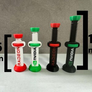 Pode incluir: Quatro objetos impressos em 3D, semelhantes a seringas, com alturas vari&aacute;veis. O maior tem 11 cm, o menor 7,5 cm. Cada um tem um &ecirc;mbolo e uma base coloridos, com o texto "RADEON" ou "NVIDIA". As cores incluem vermelho, branco, verde e preto.