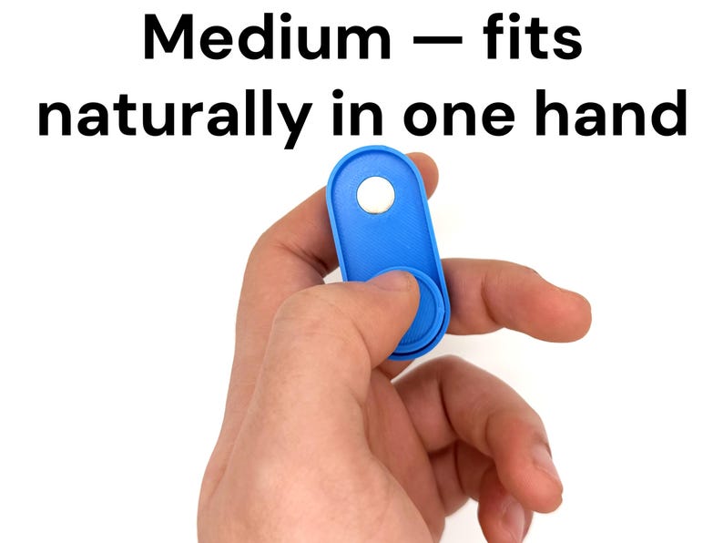 May include: A blue fidget toy with a circular button and a hole, held in a hand. The text "Medium - fits naturally in one hand" is above the toy. The toy is designed to fit comfortably in the hand.