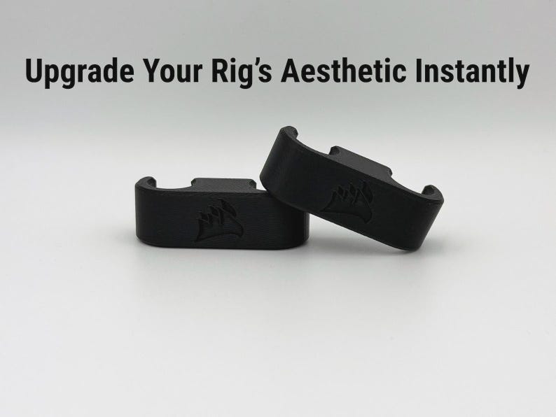 May include: Two black computer component accessories are shown against a white backdrop. The text "Upgrade Your Rig's Aesthetic Instantly" is above the components. The accessories are curved and feature a logo. They have a slot on top.