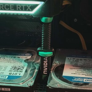 Pode incluir: Um componente de computador com o texto "FORCE RTX" e um suporte NVIDIA verde. O suporte est&aacute; posicionado entre dois discos r&iacute;gidos. Os discos r&iacute;gidos t&ecirc;m o texto "WD Blue" e "1.0TB" neles.