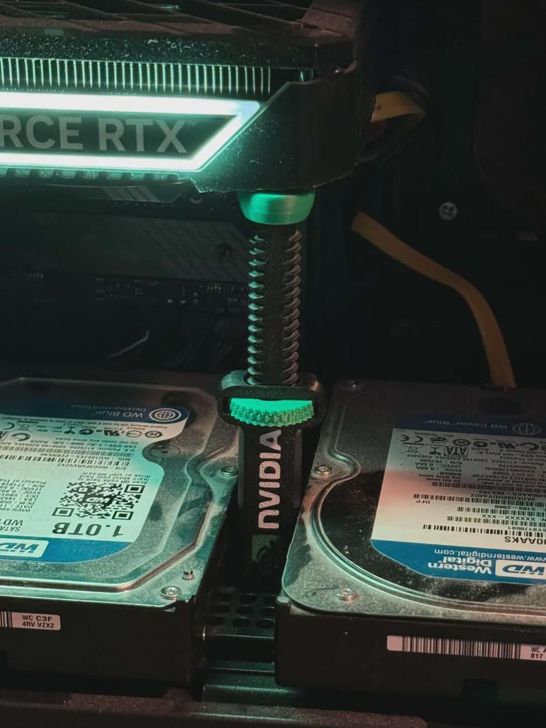 Pode incluir: Um componente de computador com o texto "FORCE RTX" e um suporte NVIDIA verde. O suporte est&aacute; posicionado entre dois discos r&iacute;gidos. Os discos r&iacute;gidos t&ecirc;m o texto "WD Blue" e "1.0TB" neles.