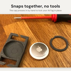 May include: A black plastic AirTag holder with a separate circular cap and a silver Apple AirTag. The text Snaps together, no tools and The cap presses in by hand to lock your AirTag in place is visible above a red and black screwdriver.