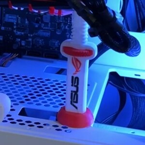 Pode incluir: Um parafuso branco e vermelho para caixa de PC ASUS ROG. O parafuso tem uma base e um topo vermelhos, com o logotipo e o texto ASUS ROG em branco. O parafuso foi projetado para fixar componentes dentro de uma caixa de computador.