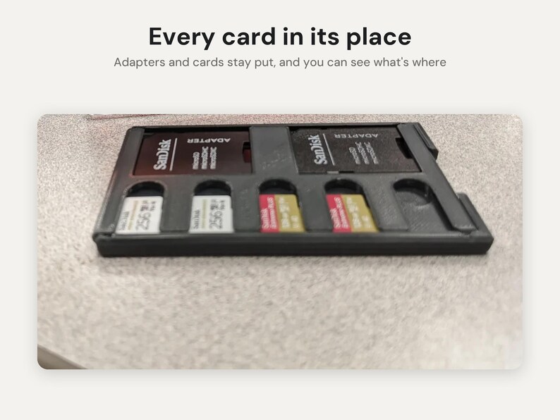 May include: A black plastic storage tray for memory cards and adapters. The tray contains two SanDisk adapters and four microSD cards. Text above the tray reads: Every card in its place. Adapters and cards stay put, and you can see what's where.