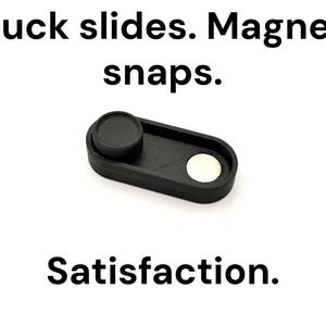 May include: A black, rectangular fidget toy with a circular puck and a silver magnet. The text "Puck slides. Magnet snaps. Satisfaction." is displayed above and below the toy on a white background.