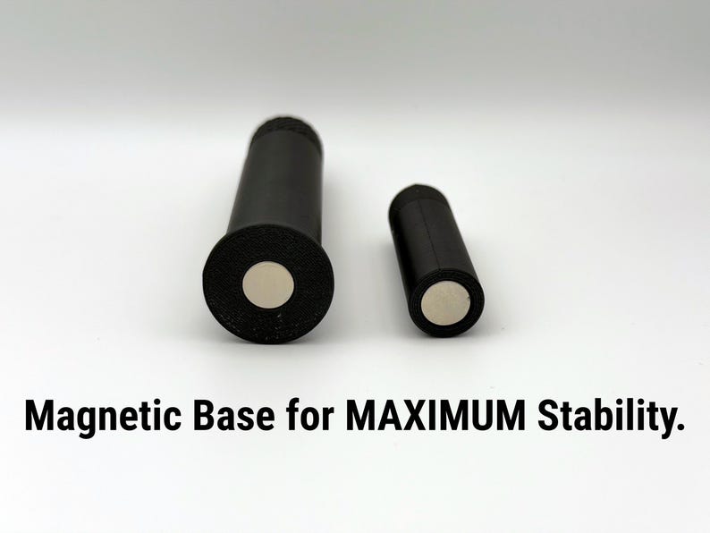 Puede incluir: Dos objetos cil&iacute;ndricos negros con bases magn&eacute;ticas se muestran sobre un fondo blanco. El cilindro m&aacute;s grande tiene una base m&aacute;s ancha. El texto "Magnetic Base for MAXIMUM Stability" est&aacute; en la parte inferior.
