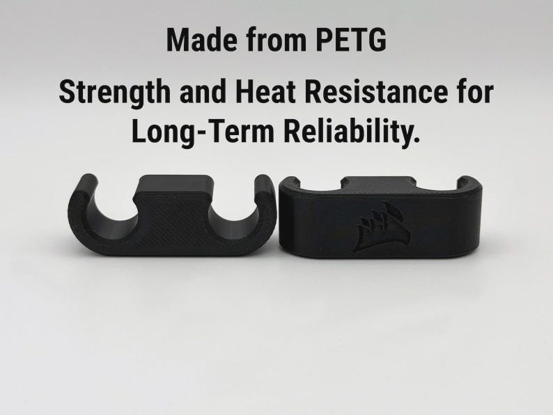 May include: Two black, curved plastic cable organisers. The text above reads "Made from PETG. Strength and Heat Resistance for Long-Term Reliability.". One organiser has a logo.