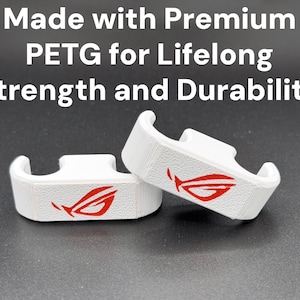 May include: Two white 3D-printed brackets with a red logo, on a dark surface. The brackets have a curved design with a slot on top. Text above reads "Made with Premium PETG for Lifelong Strength and Durability."