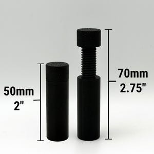 Puede incluir: Dos objetos cil&iacute;ndricos negros con tapas texturizadas. Uno mide 50 mm de alto, el otro 70 mm de alto y tiene un eje roscado. Los objetos est&aacute;n sobre un fondo gris claro.