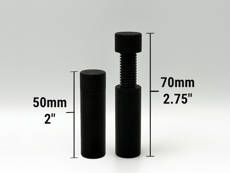 Puede incluir: Dos objetos cil&iacute;ndricos negros con tapas texturizadas. Uno mide 50 mm de alto, el otro 70 mm de alto y tiene un eje roscado. Los objetos est&aacute;n sobre un fondo gris claro.