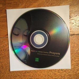 May include: A CD in a white paper sleeve. The CD has a black surface with a woman's face and the text "Sumi Jo | James Conlon Prayers". The CD is iridescent.