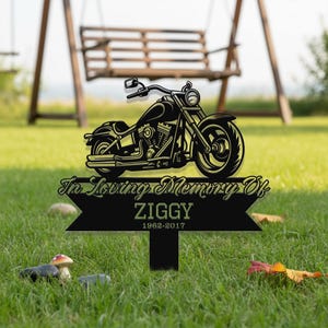 May include: Black metal motorcycle memorial garden stake with the text "In Loving Memory Of" and the name "ZIGGY" with the years 1962-2017. The motorcycle is a detailed silhouette.