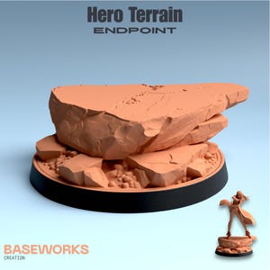 May include: A 3D-printed Hero Terrain Endpoint model, featuring a layered rock formation in a reddish-brown hue. The terrain sits on a black base with the text "Hero Terrain Endpoint" and "BASEWORKS CREATION". A miniature figure stands nearby.