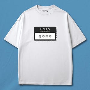 May include: White t-shirt with a black and white name tag graphic that reads "HELLO my name is... gone". The shirt has short sleeves and a crew neck. The background is a solid blue.