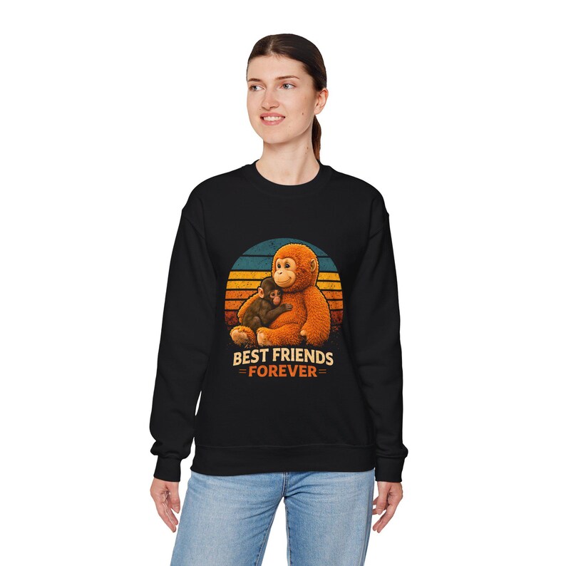 May include: Black sweatshirt featuring a graphic of two orangutans hugging, set against a sunset design. The text "BEST FRIENDS = FOREVER=" is below the image. The sweatshirt is worn by a person.