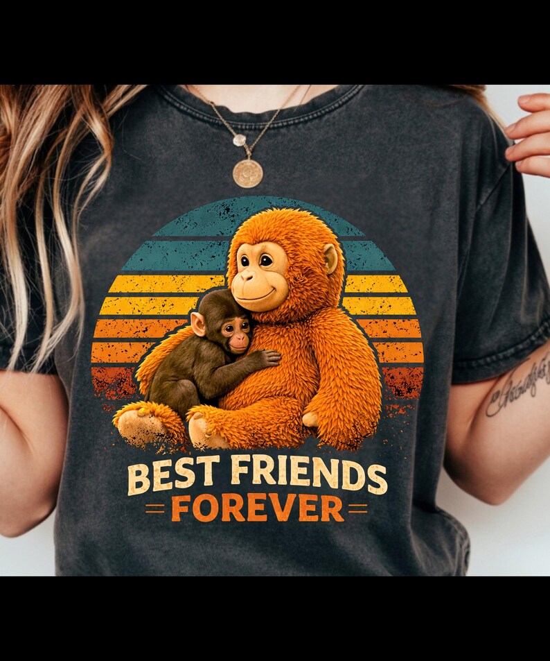May include: Dark gray t-shirt featuring a graphic of two cartoon orangutans hugging, set against a sunset design with blue, yellow, and orange stripes. The text "BEST FRIENDS FOREVER" is printed below the image.