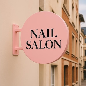 Peut inclure: Un panneau de salon de manucure rose en forme de cercle. Le panneau affiche les mots « NAIL SALON » en noir, en gras. Le panneau est monté sur un mur avec un support rose assorti. Le panneau est de couleur rose clair.