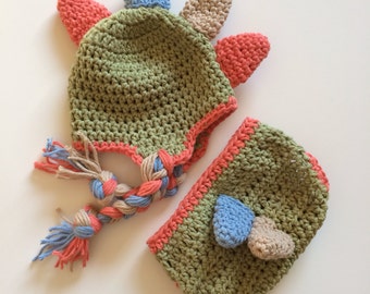 May include: A green crocheted hat and matching trousers set with colourful crocheted spikes and a braided tail. The hat has a fold-down flap.