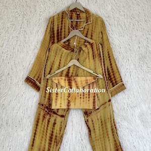 May include: A tie-dye pajama set in shades of yellow and brown, with white trim. The set includes a long-sleeved top, pants, and a matching clutch with a tassel. The text "Sister Collaboration" is visible.