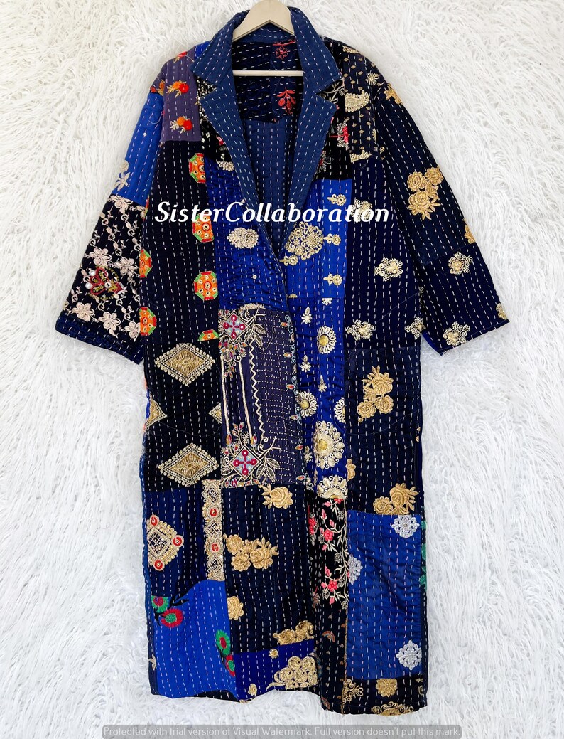 May include: A patchwork robe in shades of blue, black, and gold, with floral and geometric patterns. The robe features a notched collar and long sleeves. The text "Sister Collaboration" is visible on the robe.