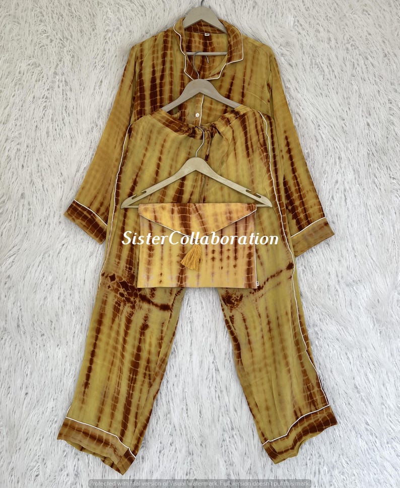 May include: A tie-dye pajama set in shades of yellow and brown, with white trim. The set includes a long-sleeved top, pants, and a matching clutch with a tassel. The text "Sister Collaboration" is visible.