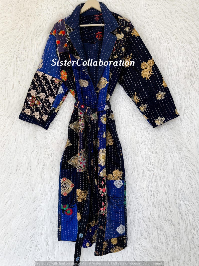 May include: A long, patchwork robe with a navy blue base, featuring various patterned fabric panels in blue, gold, and red. The robe has a belt and the text "Sister Collaboration".