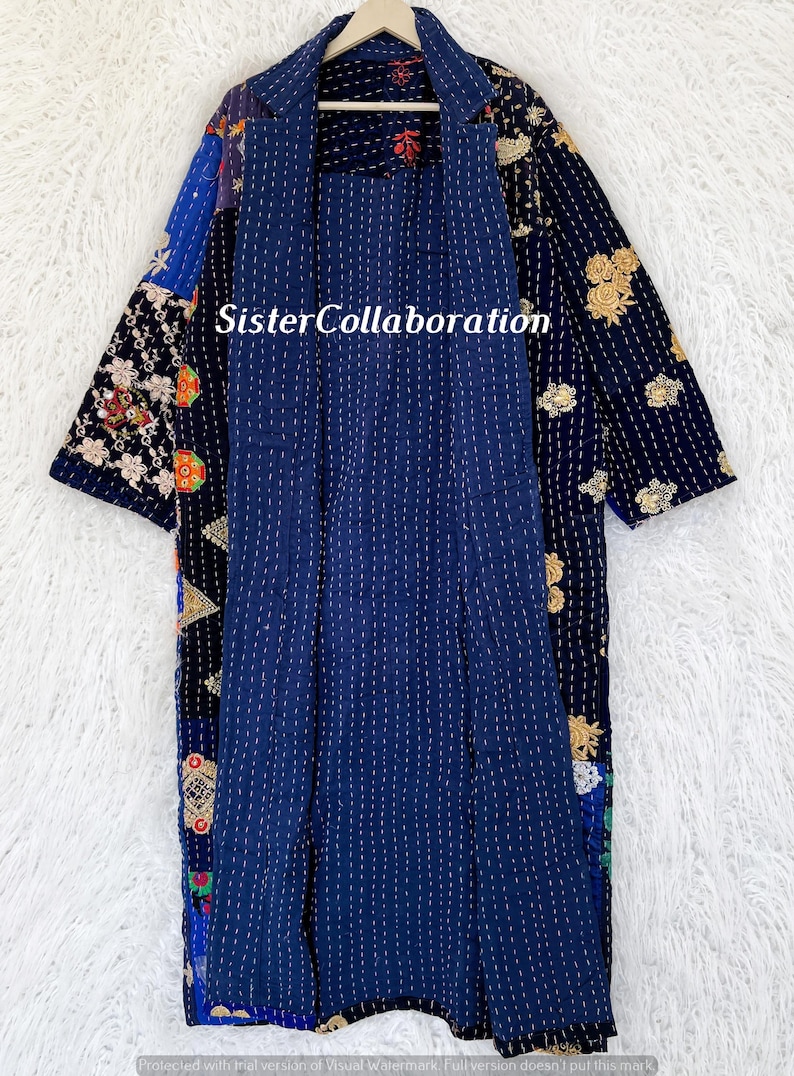 May include: A navy blue patchwork jacket with a collared neckline and open front. The jacket features floral and geometric patterns. The text "Sister Collaboration" is visible on the jacket.
