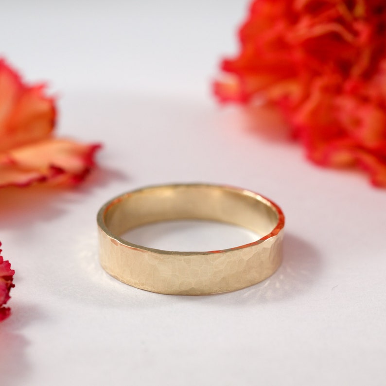 May include: A hammered gold wedding band with a matte finish.