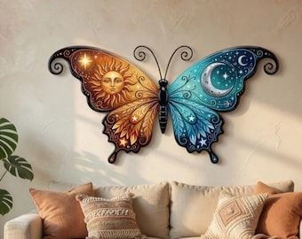 Könnte beinhalten: Ein großer, dekorativer Schmetterling als Wandkunst. Ein Flügel zeigt ein Sonnendesign in Orange und Gold, der andere einen Mond und Sterne in Blau und Türkis. Der Schmetterling ist an einer Wand in neutralen Tönen über einem beigen Sofa angebracht.