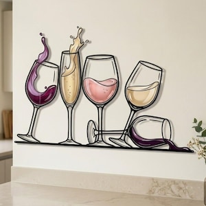 Op de afbeelding: Een wanddecoratie van zwart metaal met vier wijnglazen. Eén glas toont opspattende paarse wijn, één champagne met een spat, één bevat roséwijn en één ligt op zijn kant met paarse wijn die uitloopt over een dunne horizontale lijn.