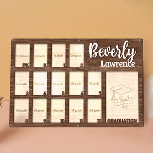 May include: Wooden graduation photo display with spaces for photos from pre-kindergarten to 12th grade. The display is personalized with the name "Beverly Lawrence" and includes a graduation cap and diploma graphic. The frame is brown with light wood inserts.