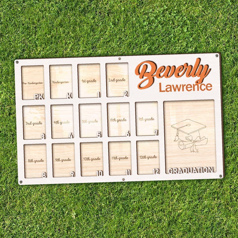 May include: A personalized wooden graduation display board with spaces for photos from pre-kindergarten through 12th grade. The board is white with the name "Beverly Lawrence" in orange script. A graduation cap and scroll are etched on the right.