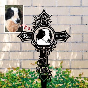 May include: Black metal pet memorial cross featuring a portrait of a dog named Boo, with the years 2015-2023. The cross is adorned with floral and scrollwork details, and a small photo of the dog.