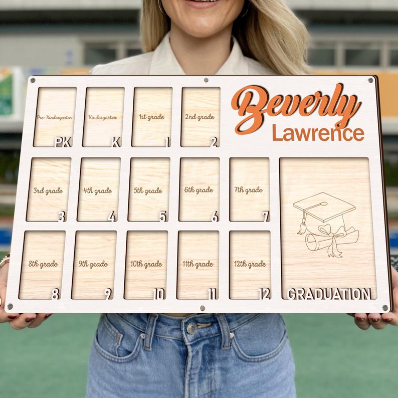 May include: A wooden graduation photo display board with slots for pre-kindergarten through 12th grade photos. The name "Beverly Lawrence" is displayed in orange script, with a graduation cap and scroll graphic. The word "GRADUATION" is at the bottom.