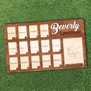 May include: A wooden graduation photo display board with spaces for photos from pre-kindergarten through 12th grade. The board is engraved with the name "Beverly Lawrence" and a graduation cap graphic. The word "GRADUATION" is also engraved.