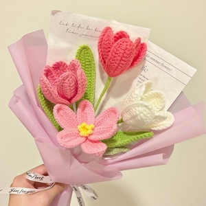 Peut inclure: Un bouquet de fleurs crochetées à la main, aux tons roses et blancs, avec des feuilles vertes. Le bouquet est enveloppé dans du papier rose et noué avec un ruban qui dit "Just for you". Comprend le texte "Let life be bea like jummone" et "like summer flowers!"