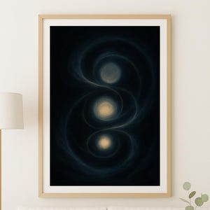Op de afbeelding: Abstracte kunstafdruk in een houten lijst. Het kunstwerk toont drie gloeiende bollen in goud en crème tegen een donkerblauwe en zwarte wervelende achtergrond. De print wordt weergegeven boven een witte bank.