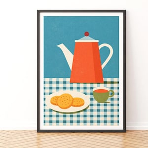 May include: A framed wall art print featuring a flat graphic illustration of a bright orange teapot, a small green teacup, and a white plate with three round golden-brown cookies. The items are set on a blue and white checkered tablecloth background.