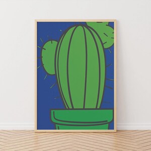 May include: A framed art print featuring a stylized green cactus in a green pot against a blue background. The cactus has dark green outlines and yellow-green spikes. The frame is a light wood color.