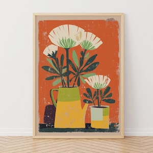 Puede incluir: Una impresión artística enmarcada que presenta una naturaleza muerta de flores estilizadas en una tetera amarilla y verde y una maceta a juego. El fondo es naranja texturizado, con flores blancas y verdes. La obra de arte tiene una estética vintage y retro.