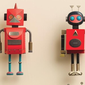 May include: Two red robot figures with geometric shapes and metallic accents. One robot has a square head with a cone on top, while the other has a rounded head with antenna-like features. Both have arms, legs, and various details.