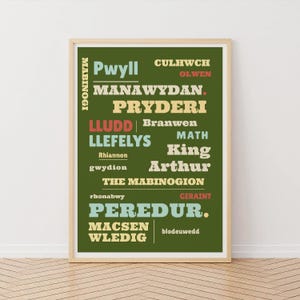 May include: A framed print with a green background and text in various colors. The text includes names like "Pwyll," "Manawydan," and "Peredur." The words "The Mabinogion" are also visible. The print is in a light-colored wooden frame.