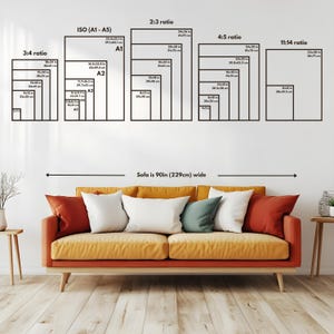 May include: A wall with various black framed art print size guides, including ISO, 2:3, 4:5, and 11:14 ratios. Below, a mustard-colored sofa with white, red, and teal pillows. The sofa is 90 inches (229cm) wide.