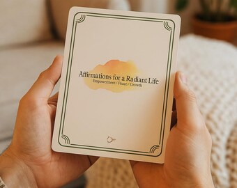 Könnte beinhalten: Eine rechteckige Karte mit dem Text "Affirmations for a Radiant Life" in schwarzer Schrift, darunter "Empowerment / Peace / Growth". Die Karte hat einen grünen Rand und ein Design im Aquarellstil. Die Karte wird in zwei Händen gehalten.