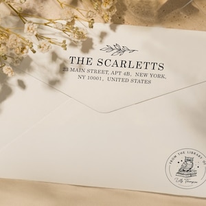 May include: Cream-colored envelope with the address "THE SCARLETTS" and address details printed in black. A circular stamp at the bottom reads "FROM THE LIBRARY OF" with an owl illustration and the name "Zilly Thompson".