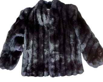 May include: A dark, luxurious fur coat with a classic design. The coat is a deep black color and features a collar and button closure. The fur appears soft and plush, with a slightly textured appearance.
