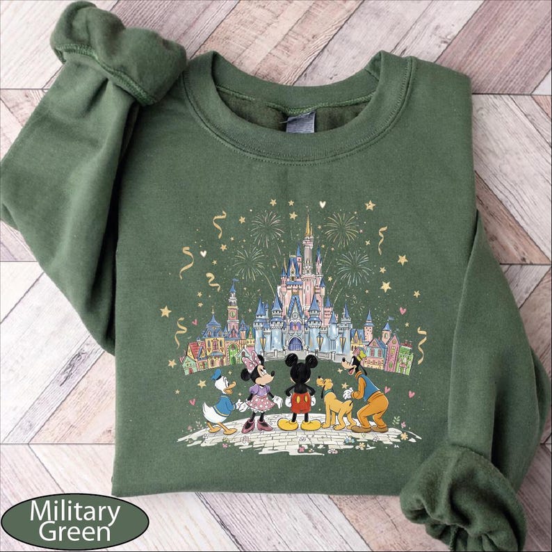 A green sweatshirt with a Disney-themed illustration of Minnie Mouse, Donald Duck, and Goofy standing in front of a castle, with fireworks in the background.