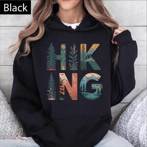 A person wearing a black hoodie with the word "HIKING" printed on it.
