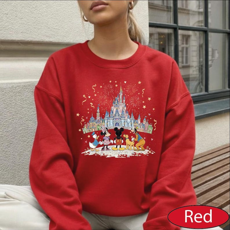 A red sweater with a Disney-themed graphic depicting Minnie Mouse, Mickey Mouse, and other Disney characters standing in front of a castle.